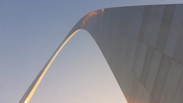 looking up at the curve of the Gateway Arch against the sky